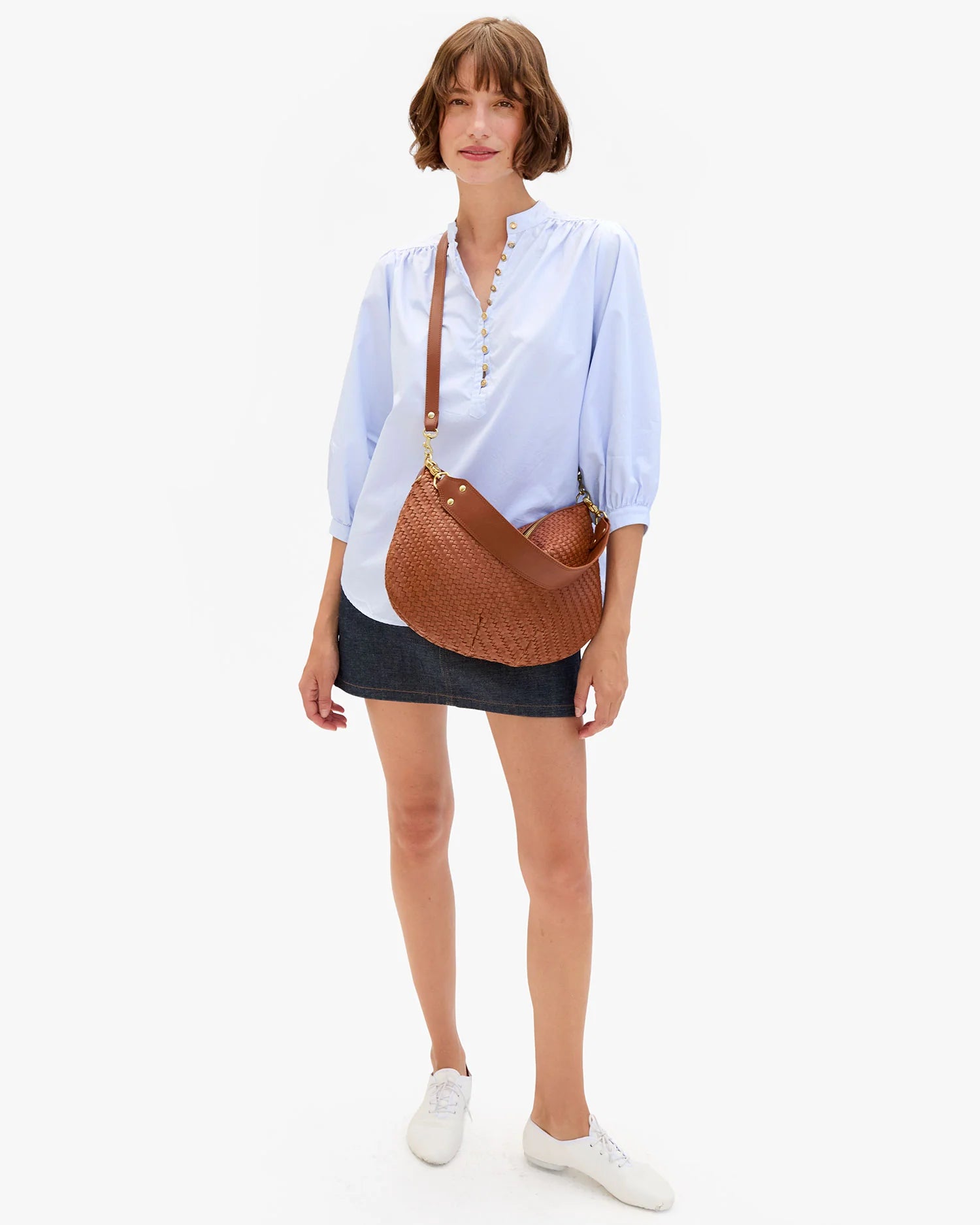 Woman holding a brown leather bag against a white background