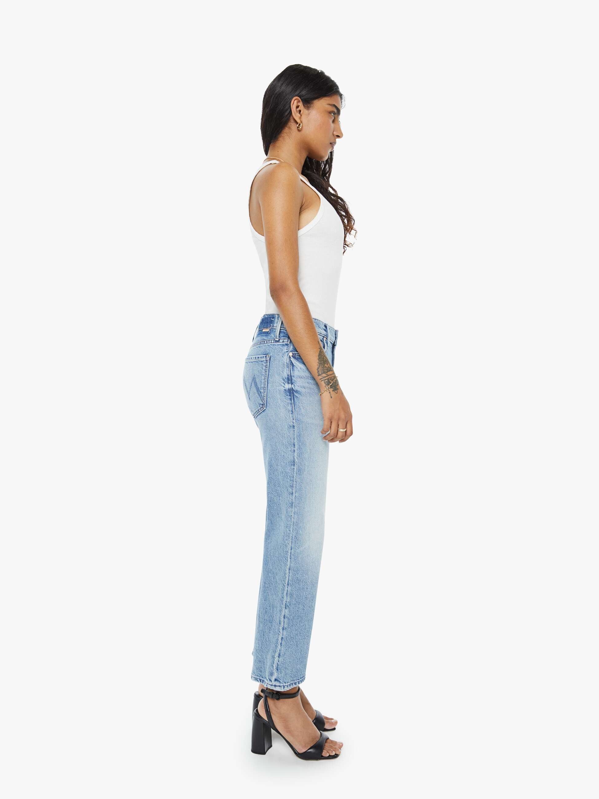Woman wearing light blue jeans and a white top on a white background