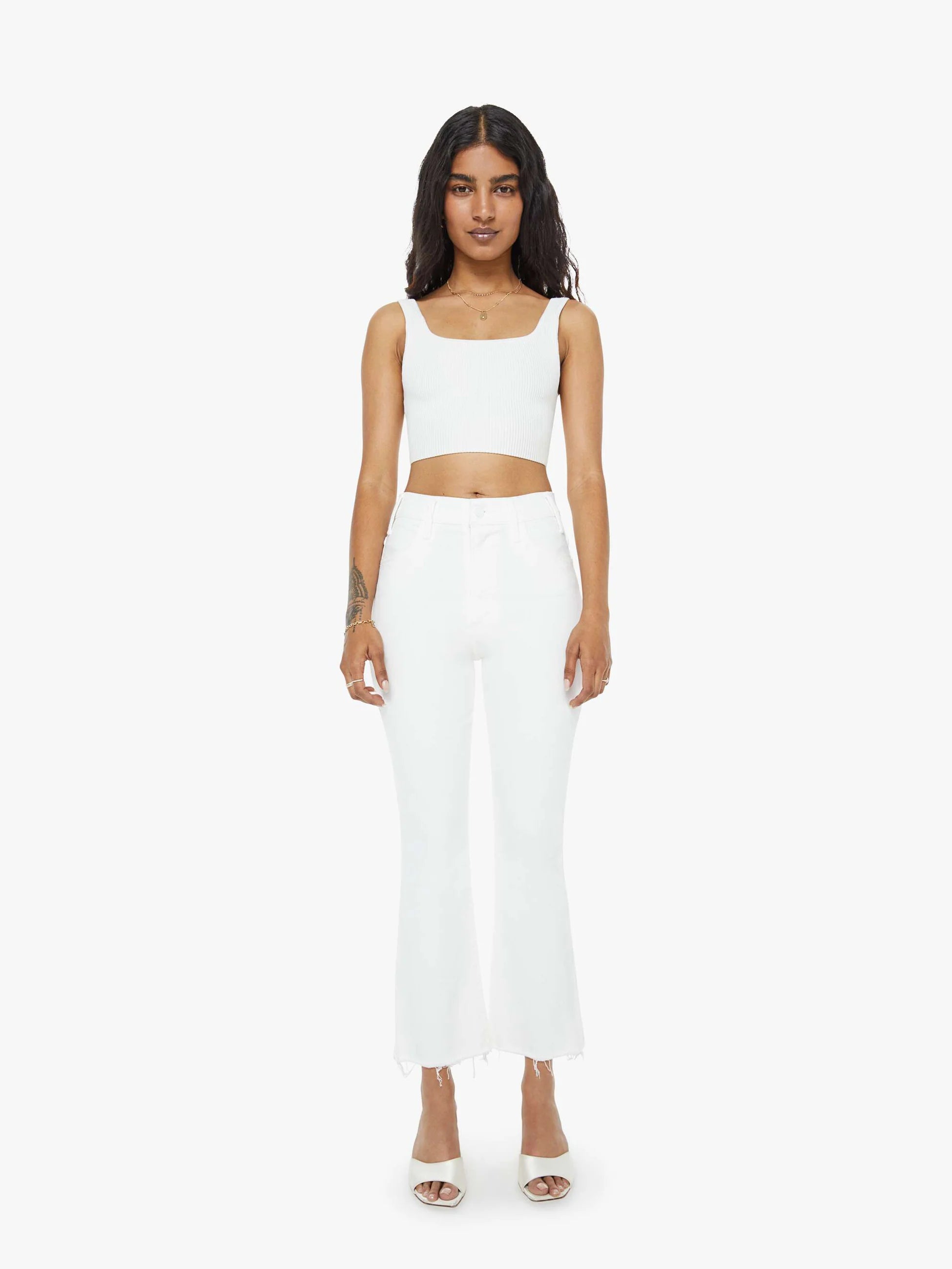 Woman wearing a white sleeveless top and long white pants on a white background