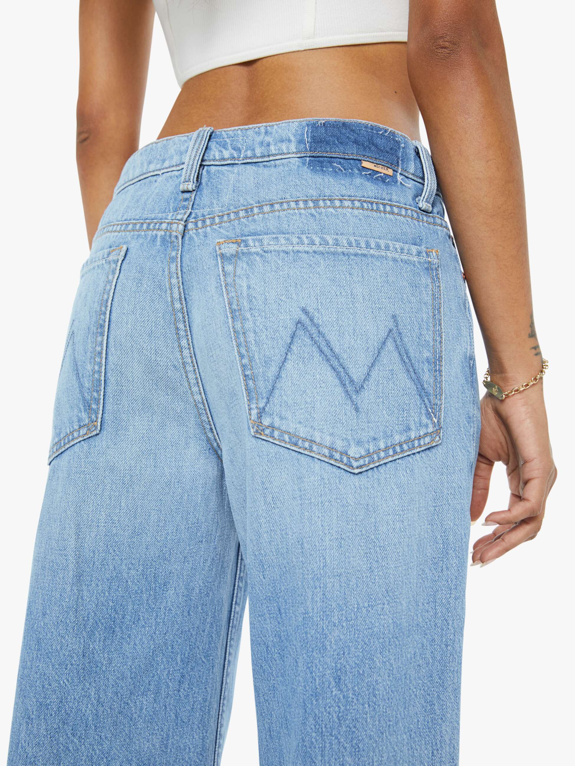 Light blue jeans with a brand logo on the back pocket against a white background