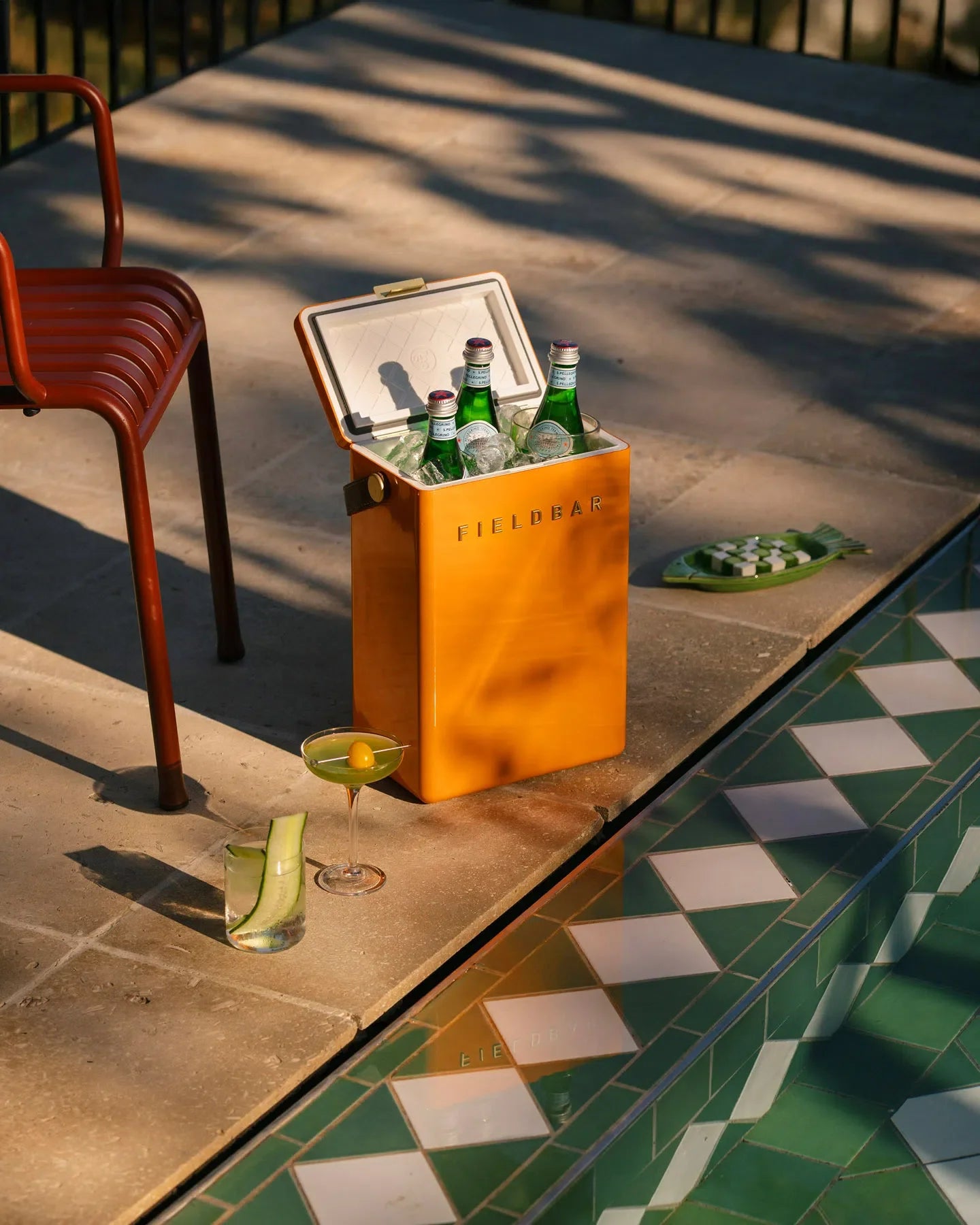 Orange cooler box with drinks by a poolside