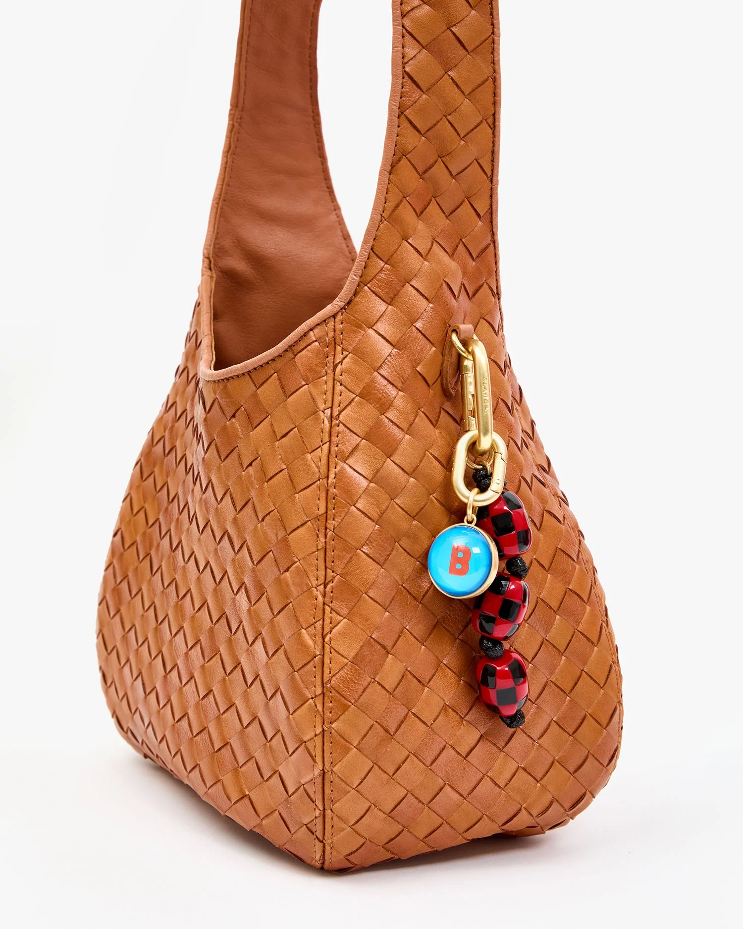 Brown woven handbag with a colorful keychain on a white background