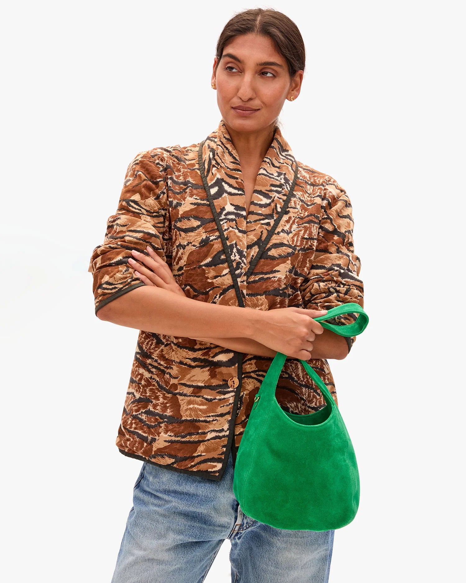 Woman wearing a patterned jacket holding a green bag on a white background