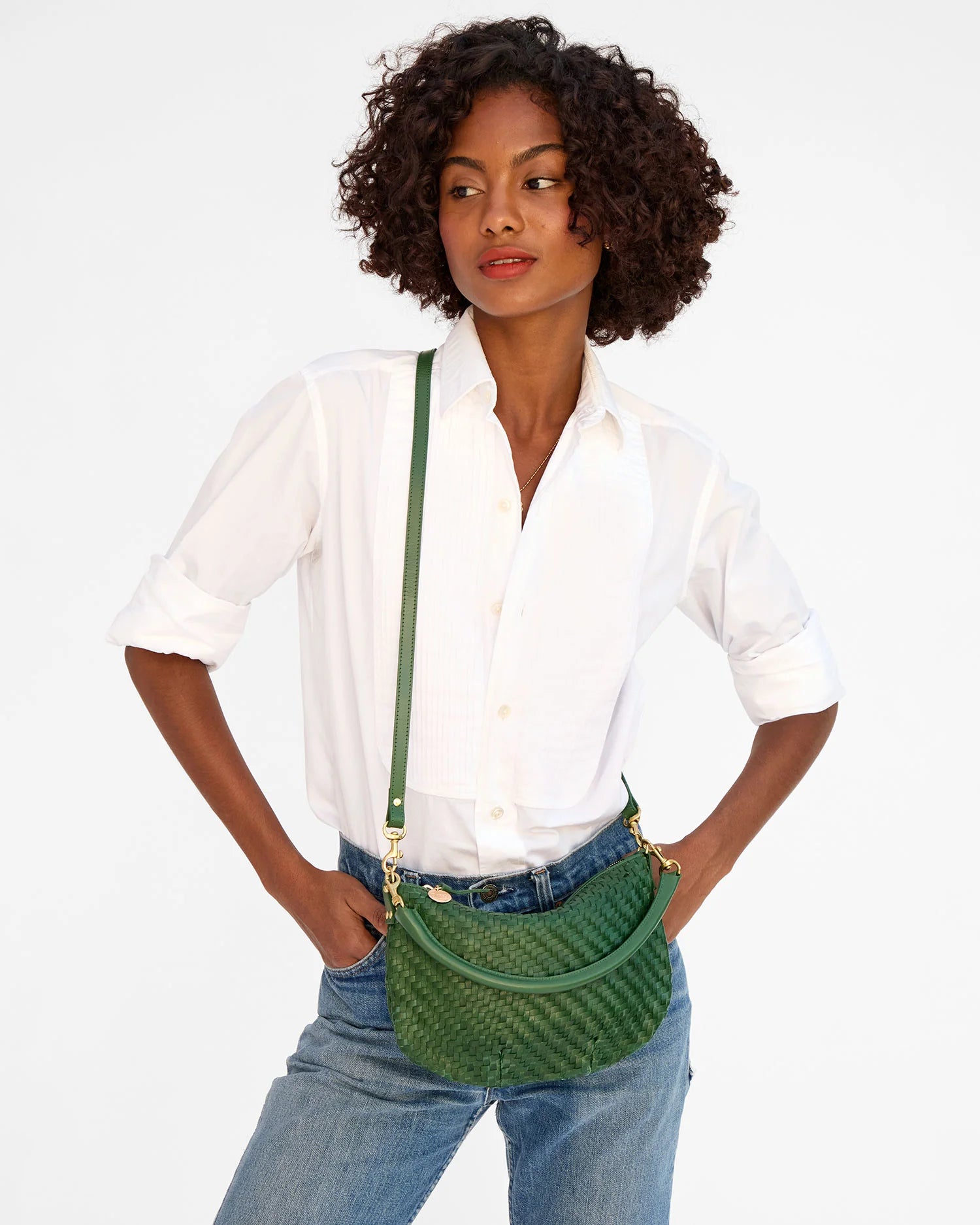 Woman wearing a green woven handbag with a plain background