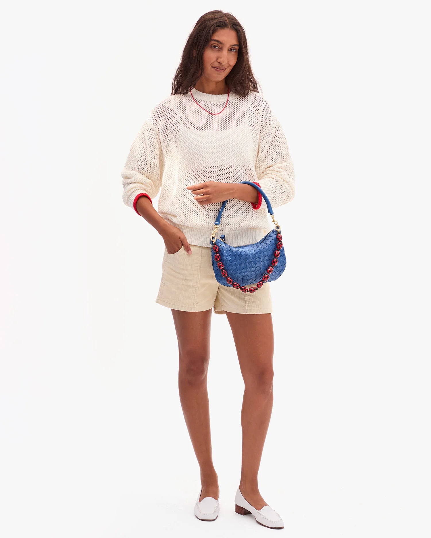 Woman holding a blue handbag against a white background