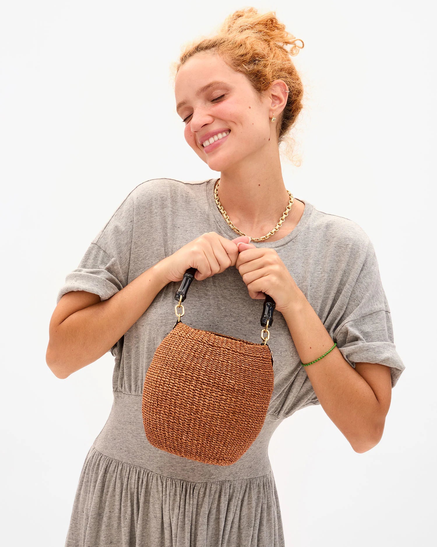 Woman holding a woven brown handbag against a white background