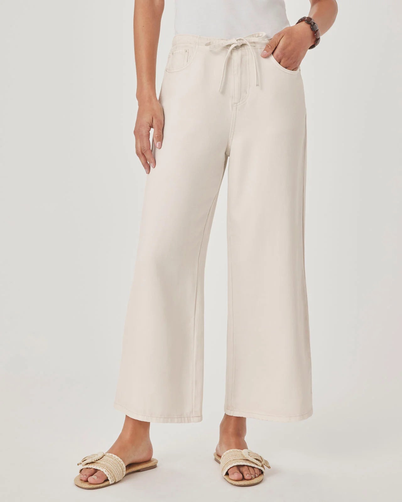 Person wearing white wide-leg pants on a plain background