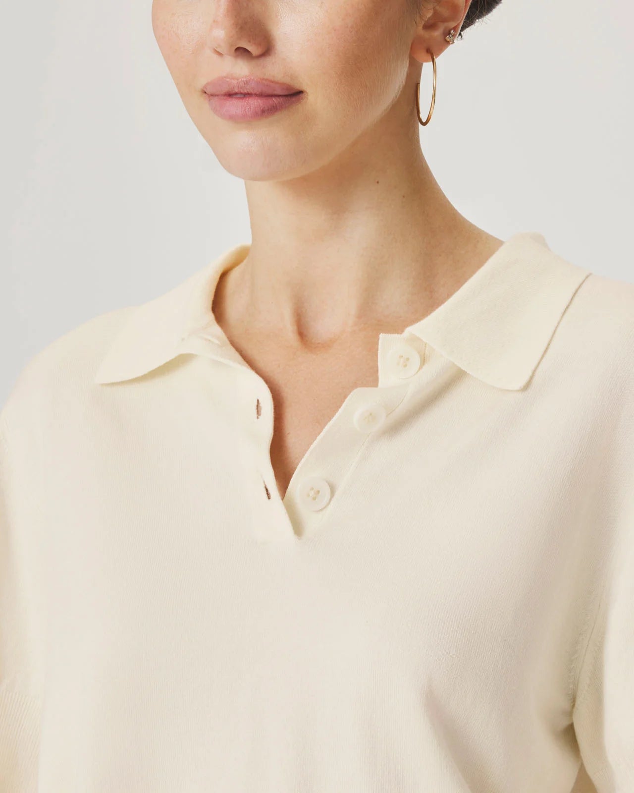 Close-up of a person wearing a light-colored shirt with a plain background