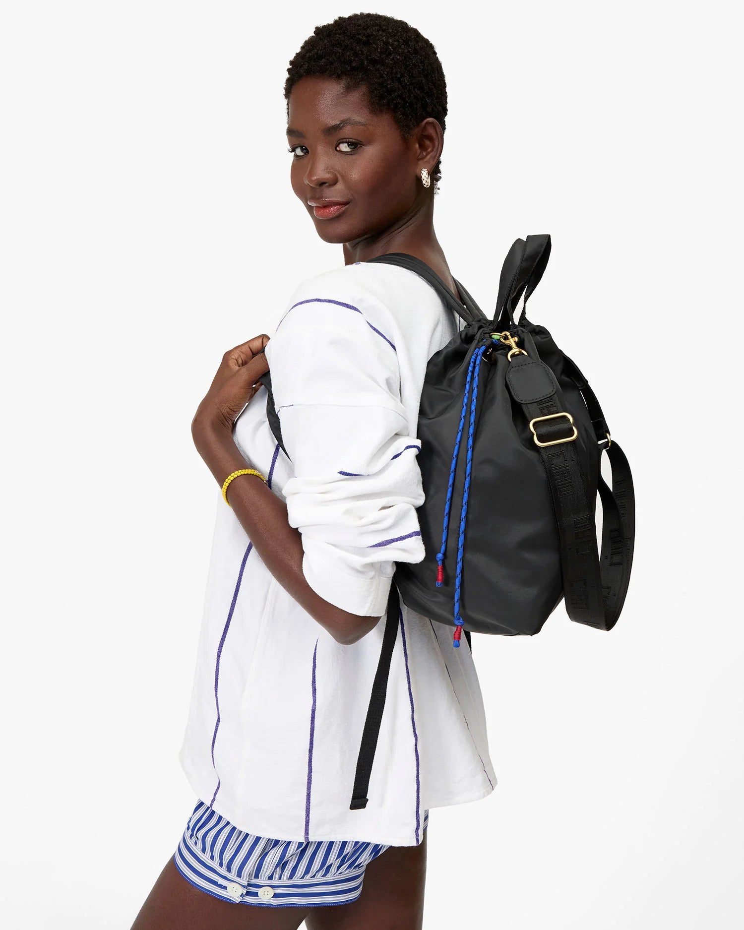 Woman wearing a black backpack with colorful drawstrings on a white background