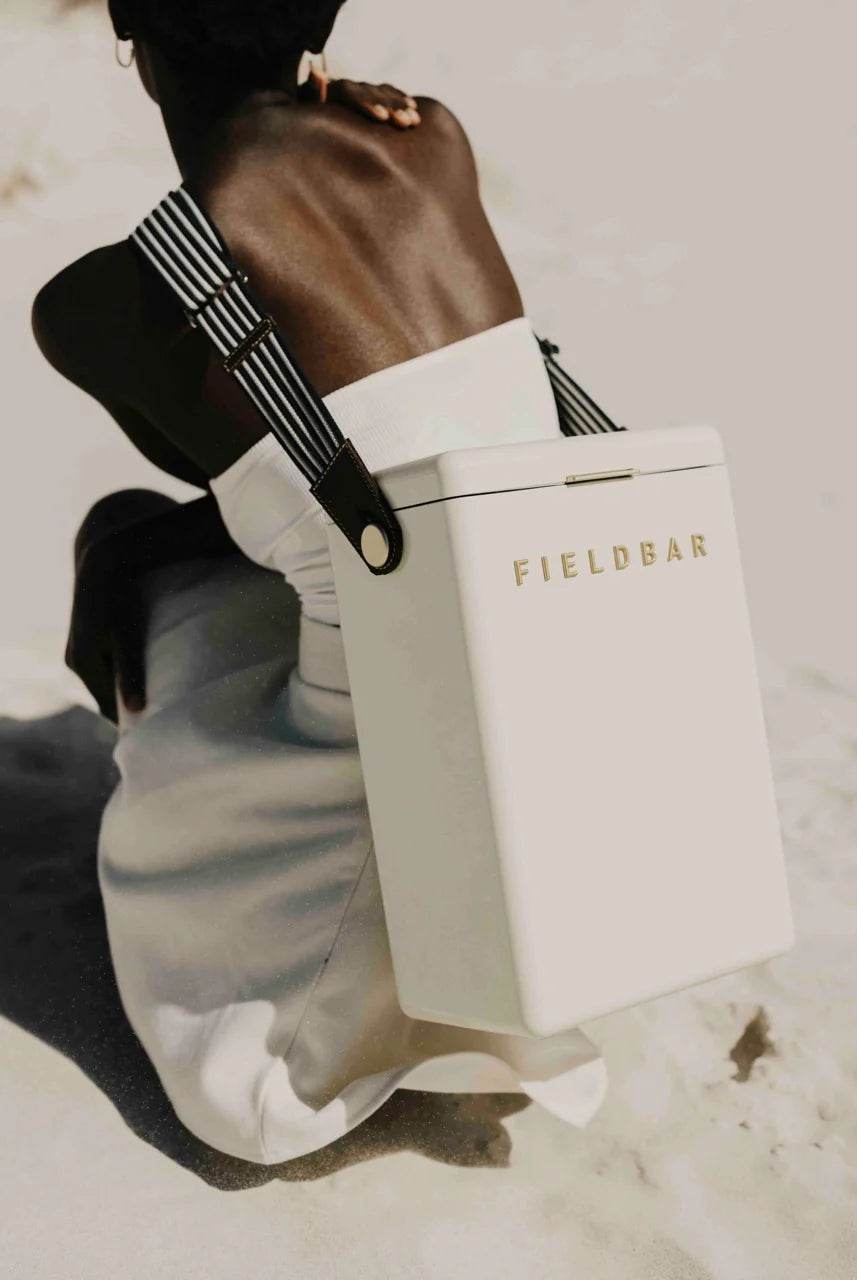 Person holding a white 'FIELDBAR' product packaging against a neutral background