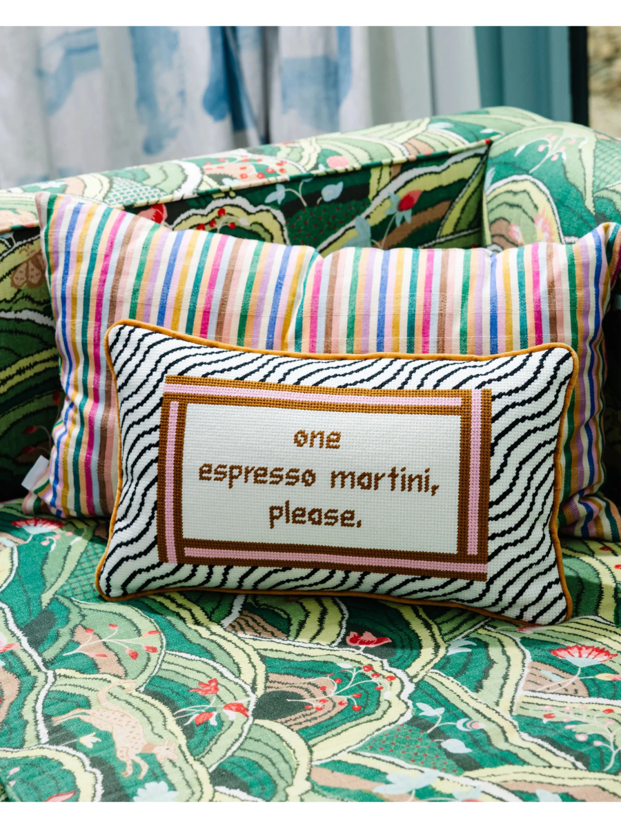 Decorative pillow with 'one espresso martini, please.' text on a patterned sofa.