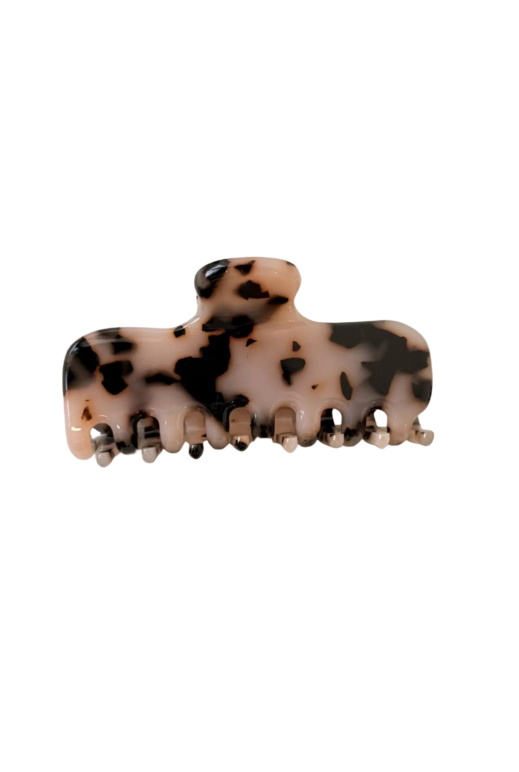 A tortoiseshell hair claw clip with a beige base and black mottled spots, shown against a plain white background.