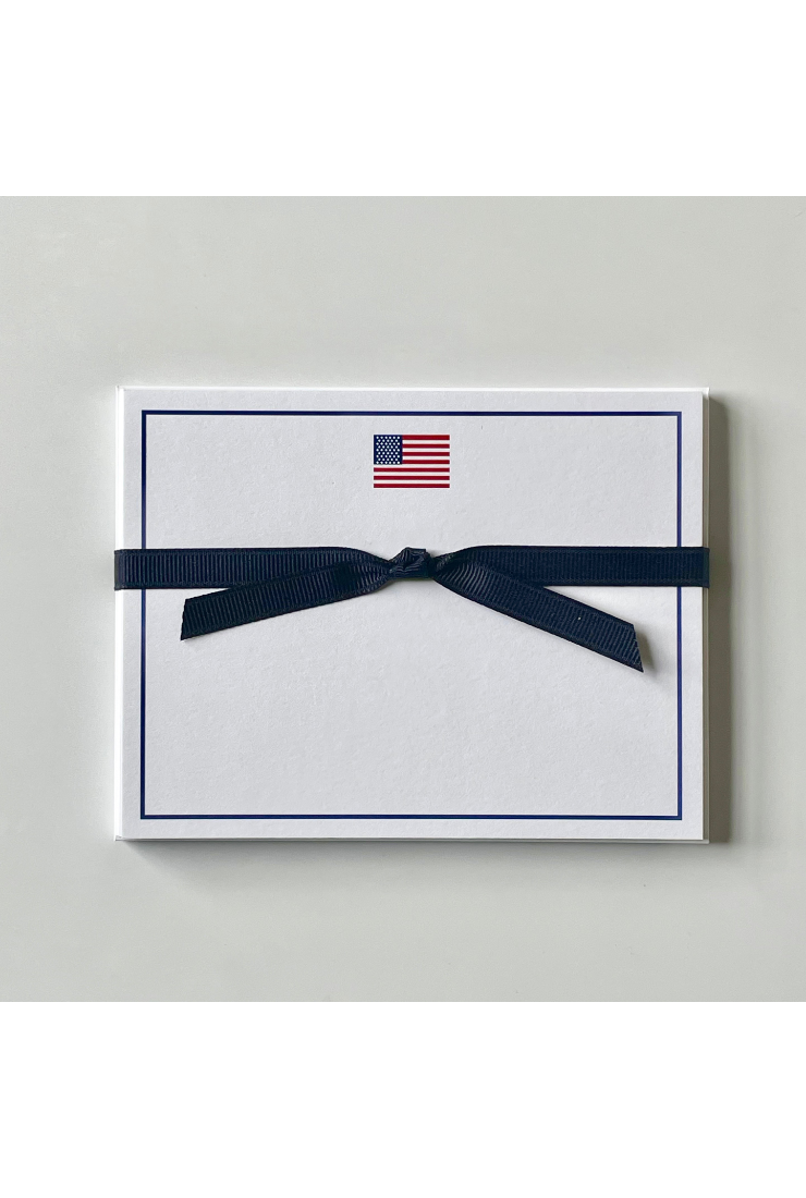 Note card with American flag design and navy ribbon on a light gray background