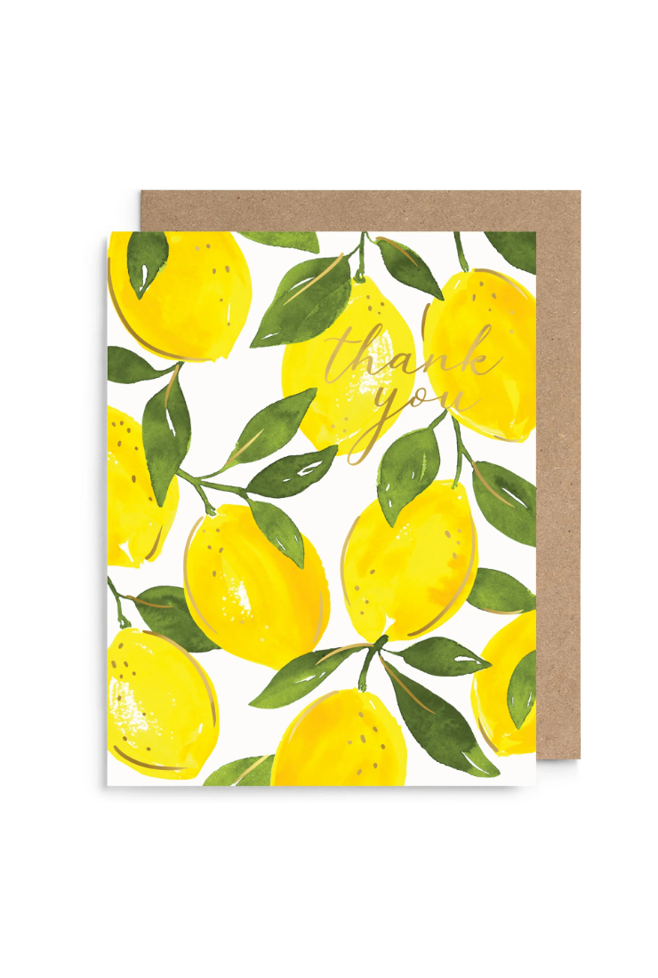 A square greeting card with a watercolor lemon pattern and the words 'thank you' in gold script, shown with a brown kraft envelope behind it on a white background.