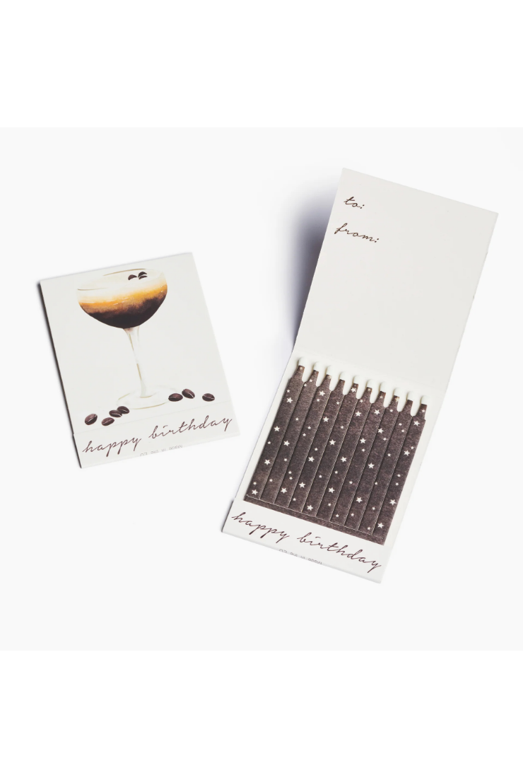 A birthday candle set with a matching card. The card features an illustration of a cocktail with coffee beans and the text 'happy birthday', while the candle holder contains multiple birthday candles with printed names on the white packaging.