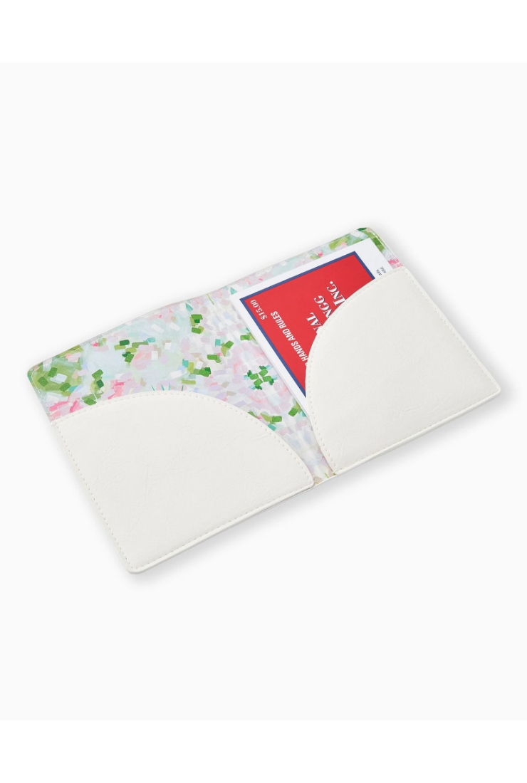 A white cardholder wallet shown open, featuring a floral patterned interior with pink and green flowers on a white background, and a red credit card partially inserted.