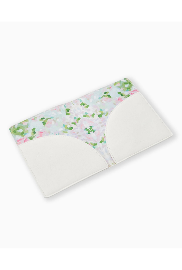 A reusable cloth menstrual cup with a white silicone flip-top closure and a floral patterned exterior featuring pink, green, and light blue flowers on a white background.