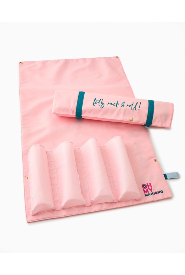 A pink fabric jewelry organizer roll with multiple compartments, shown partially unrolled with a matching rolled section placed on top. The top section has teal elastic bands and teal embroidered text reading 'let's rock 'roll!'.