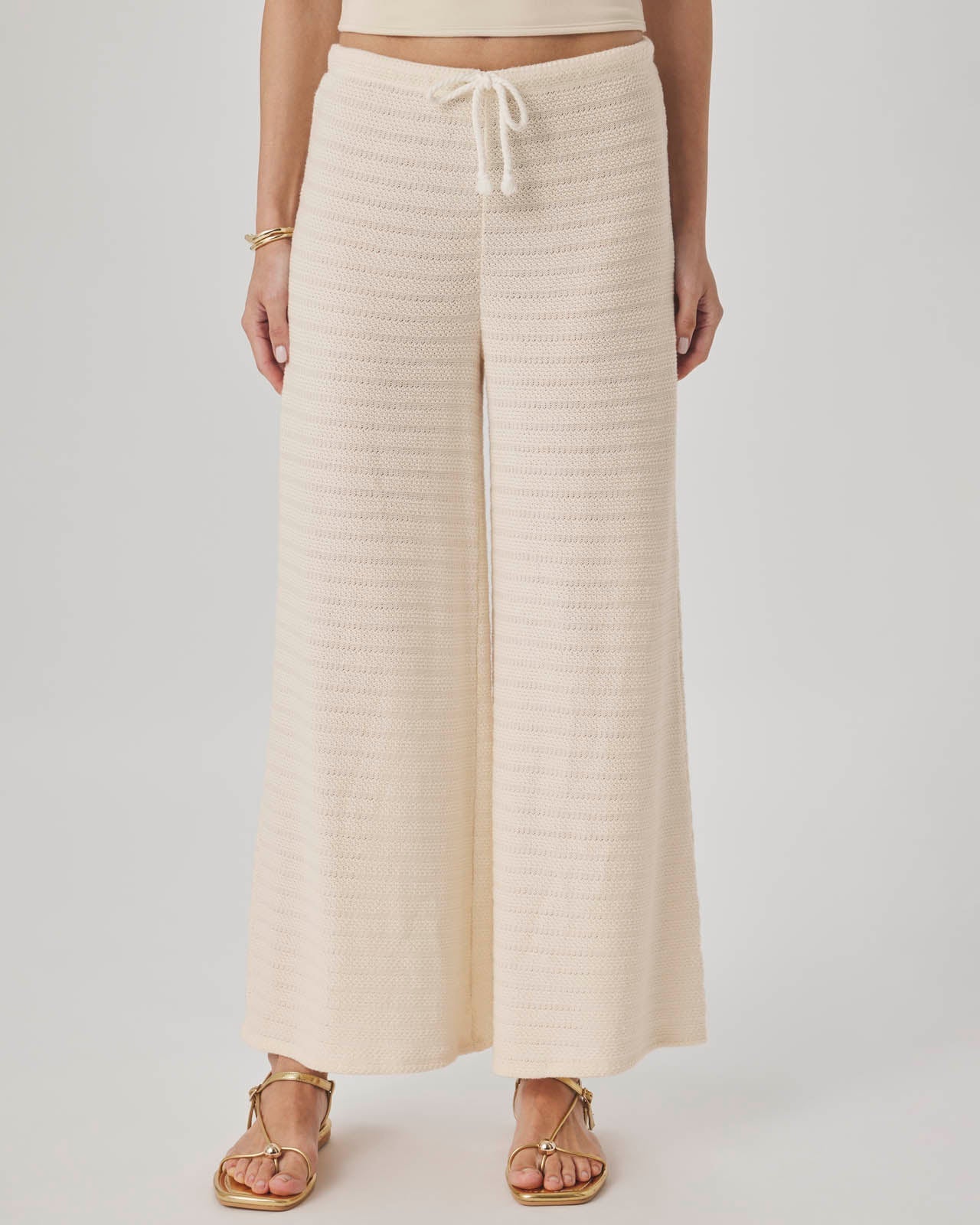 Person wearing beige wide-leg pants on a plain background