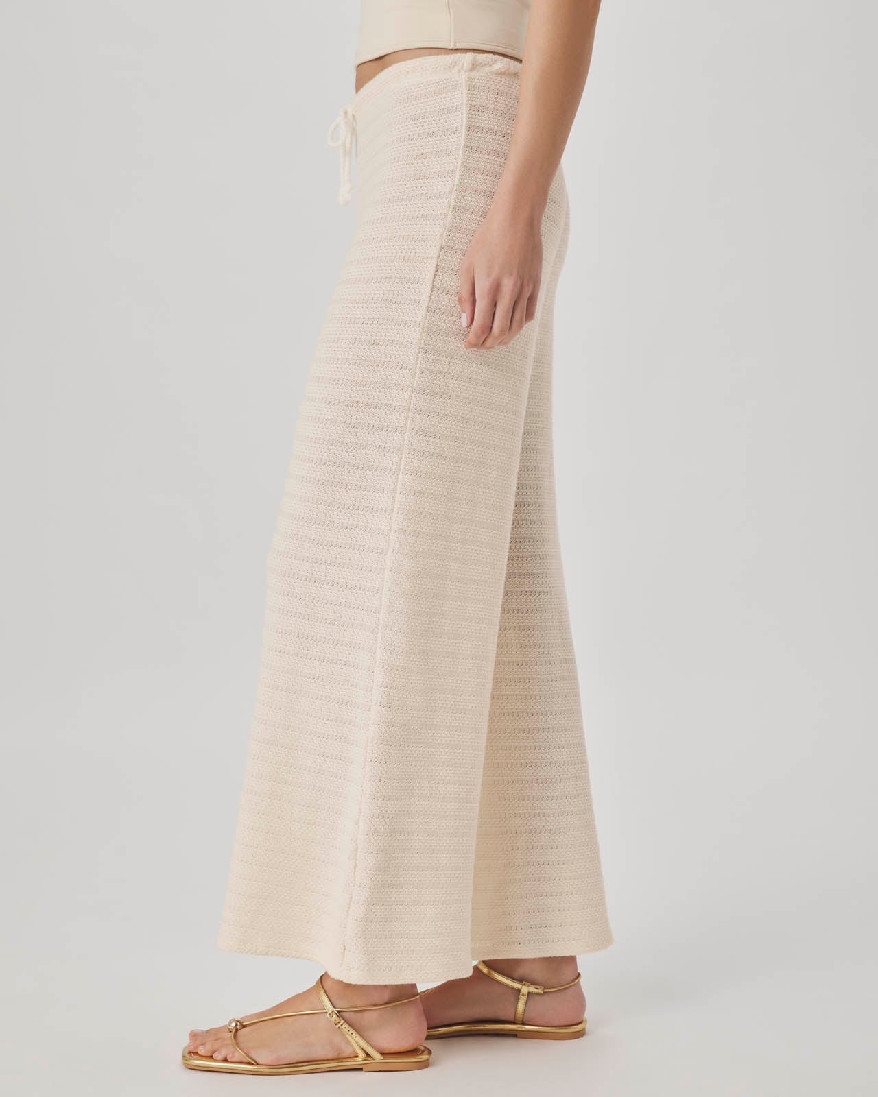 Person wearing a beige ribbed knit skirt on a plain background