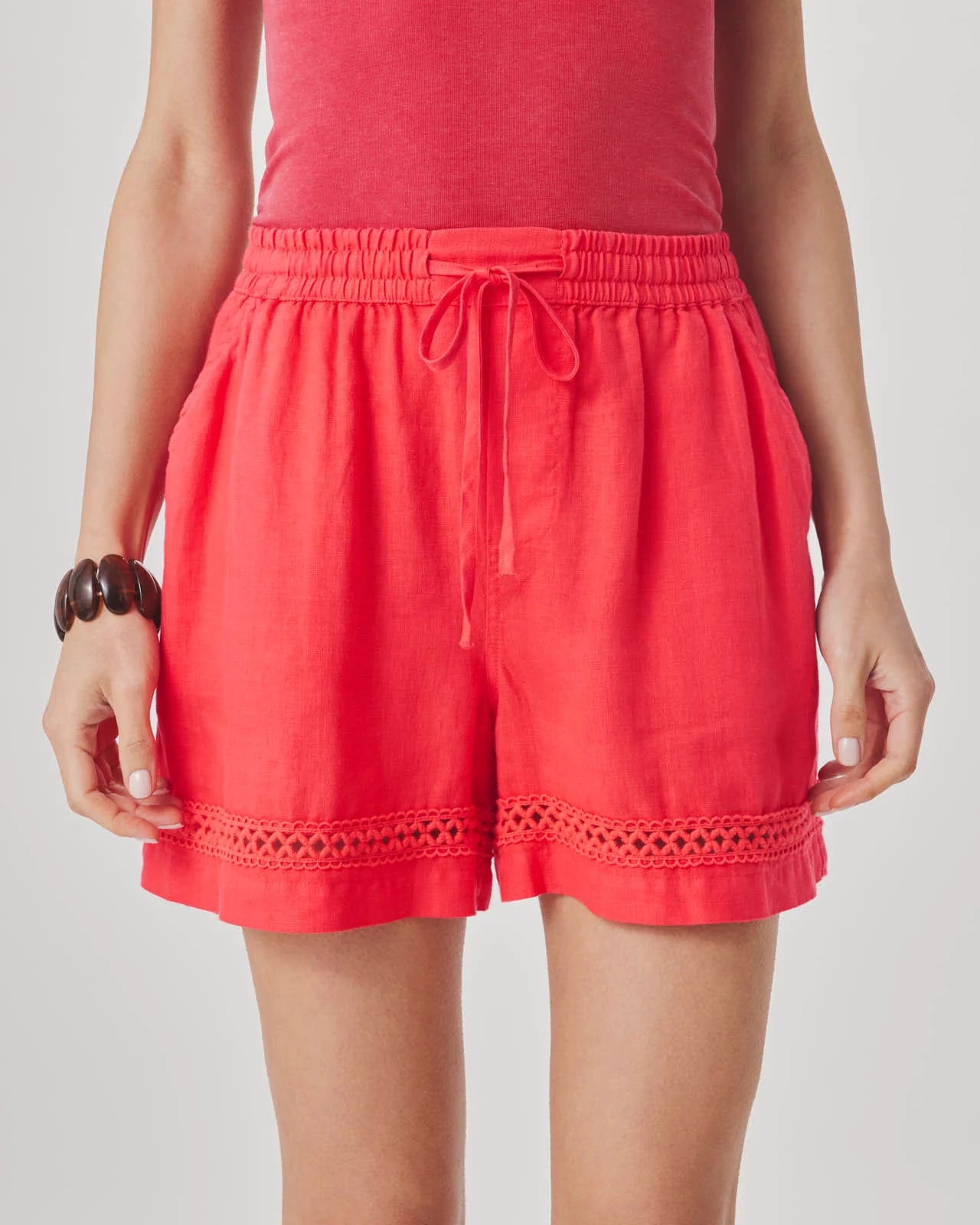 Red shorts worn by a person on a plain background