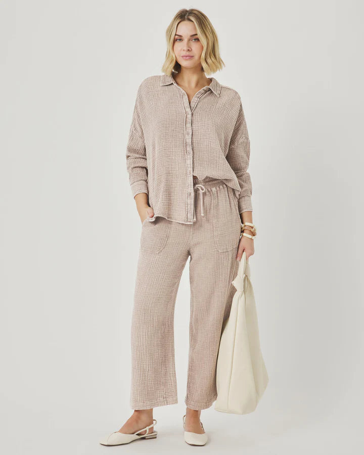Woman wearing a beige checkered outfit with a white bag on a plain background