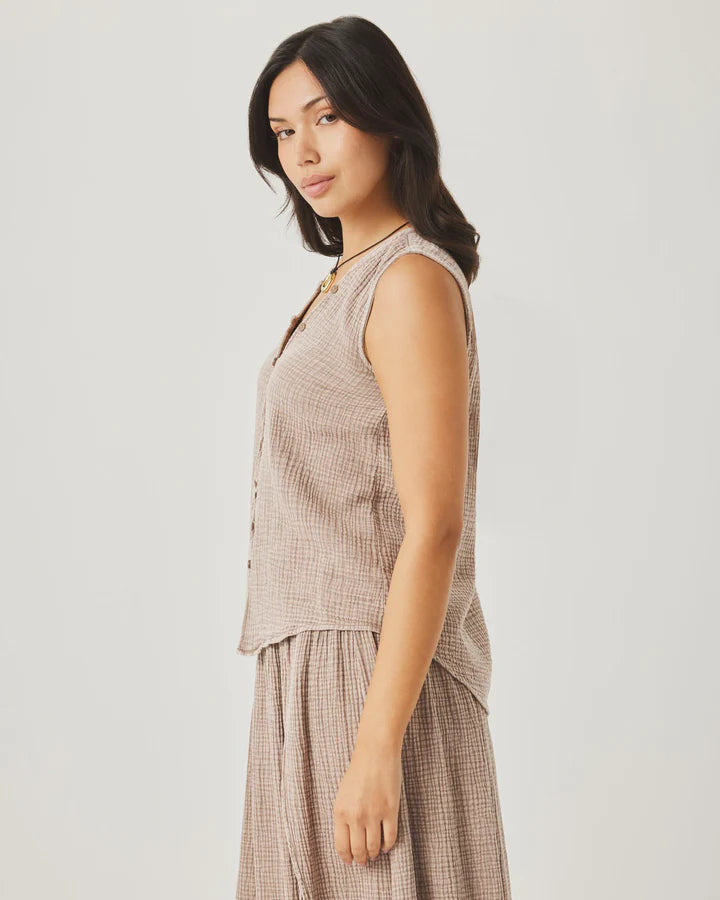 Woman wearing a sleeveless checkered top and pants on a plain background
