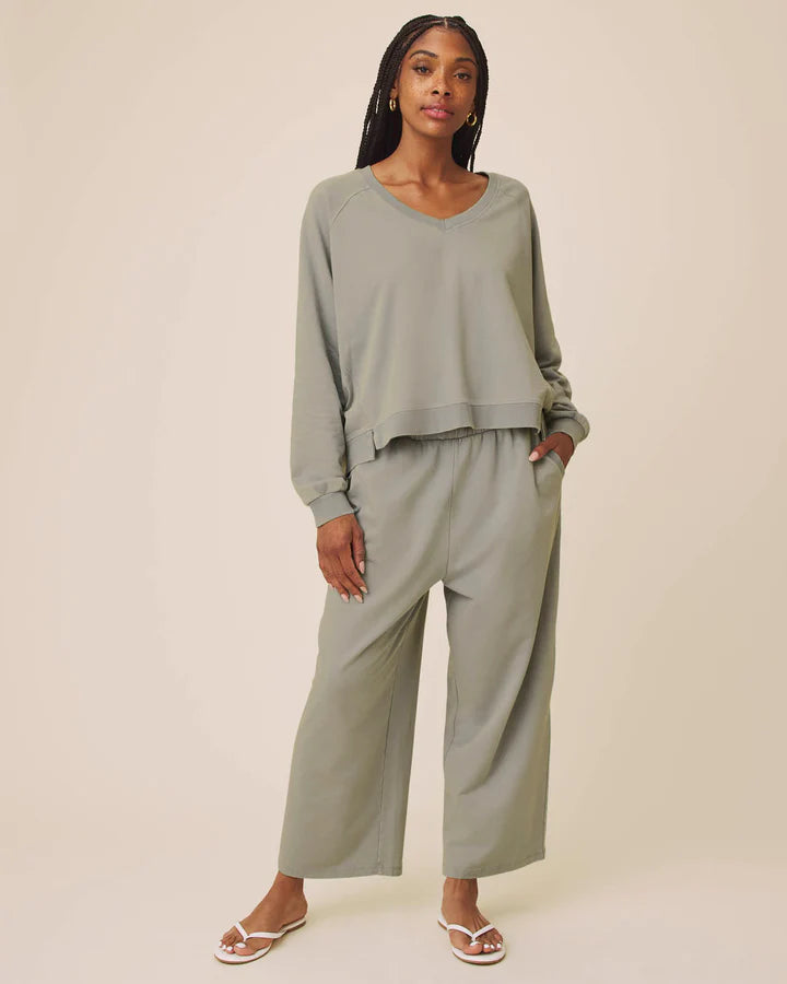 Woman wearing a matching green outfit with wide-leg pants on a beige background