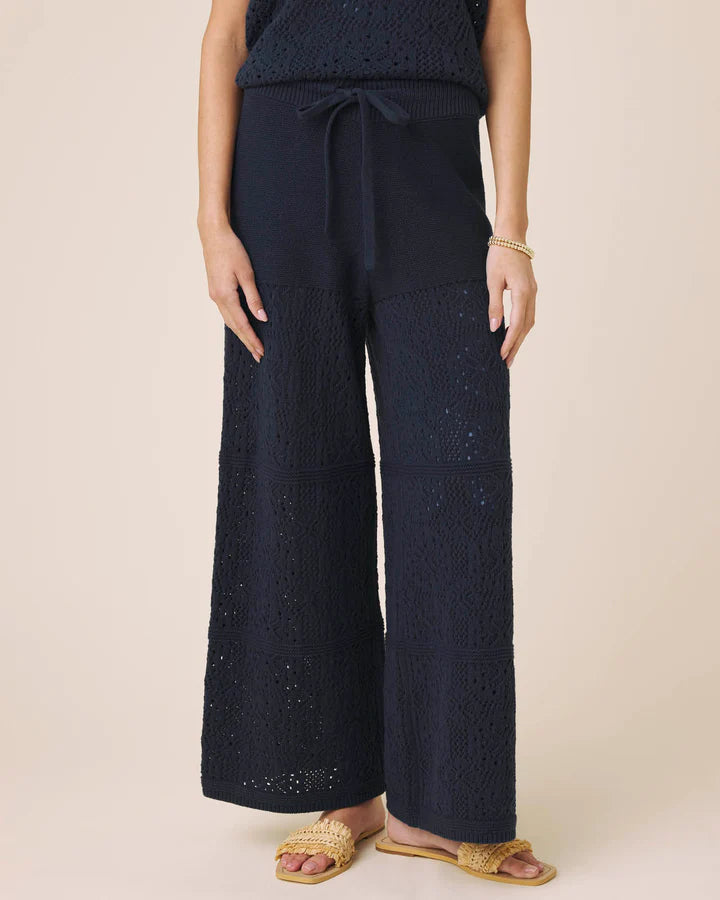 Person wearing navy blue textured pants on a beige background