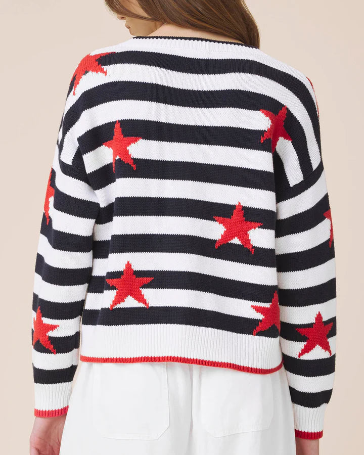 Navy and white striped sweater with red stars worn by a person on a beige background