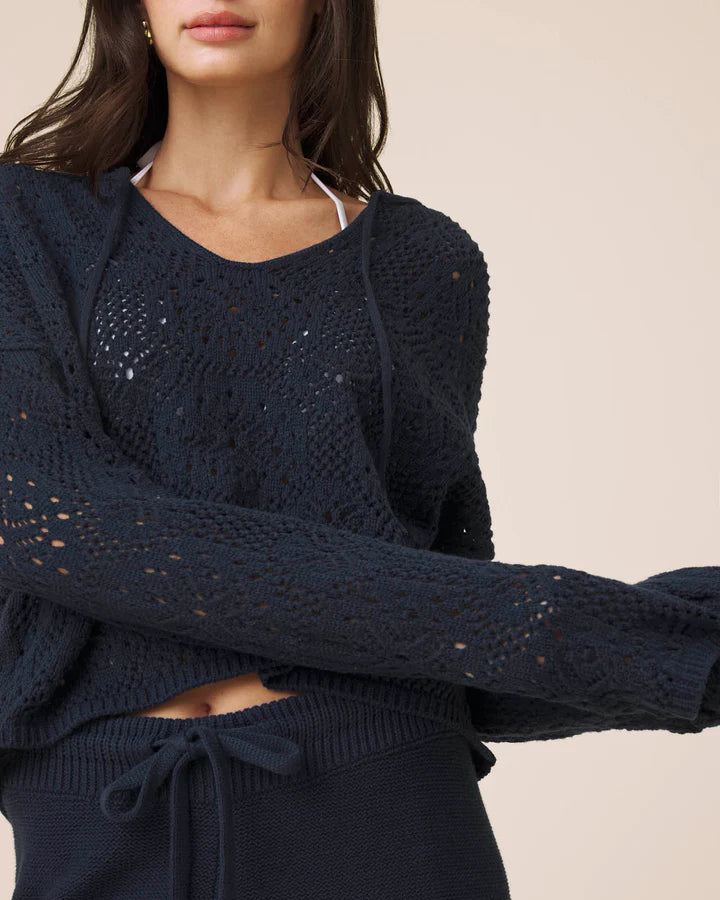 Navy blue knitted sweater worn by a person on a beige background
