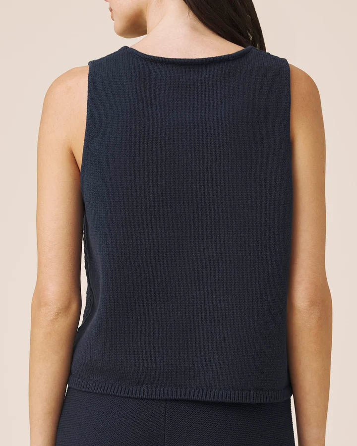 Navy sleeveless top worn by a person on a beige background
