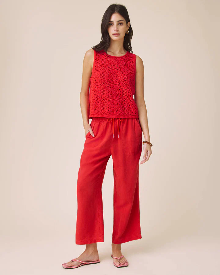 Woman wearing a red sleeveless top and pants on a beige background