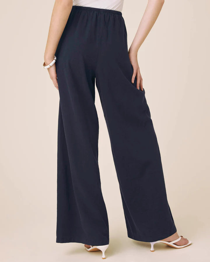 Person wearing navy wide-leg pants on a beige background
