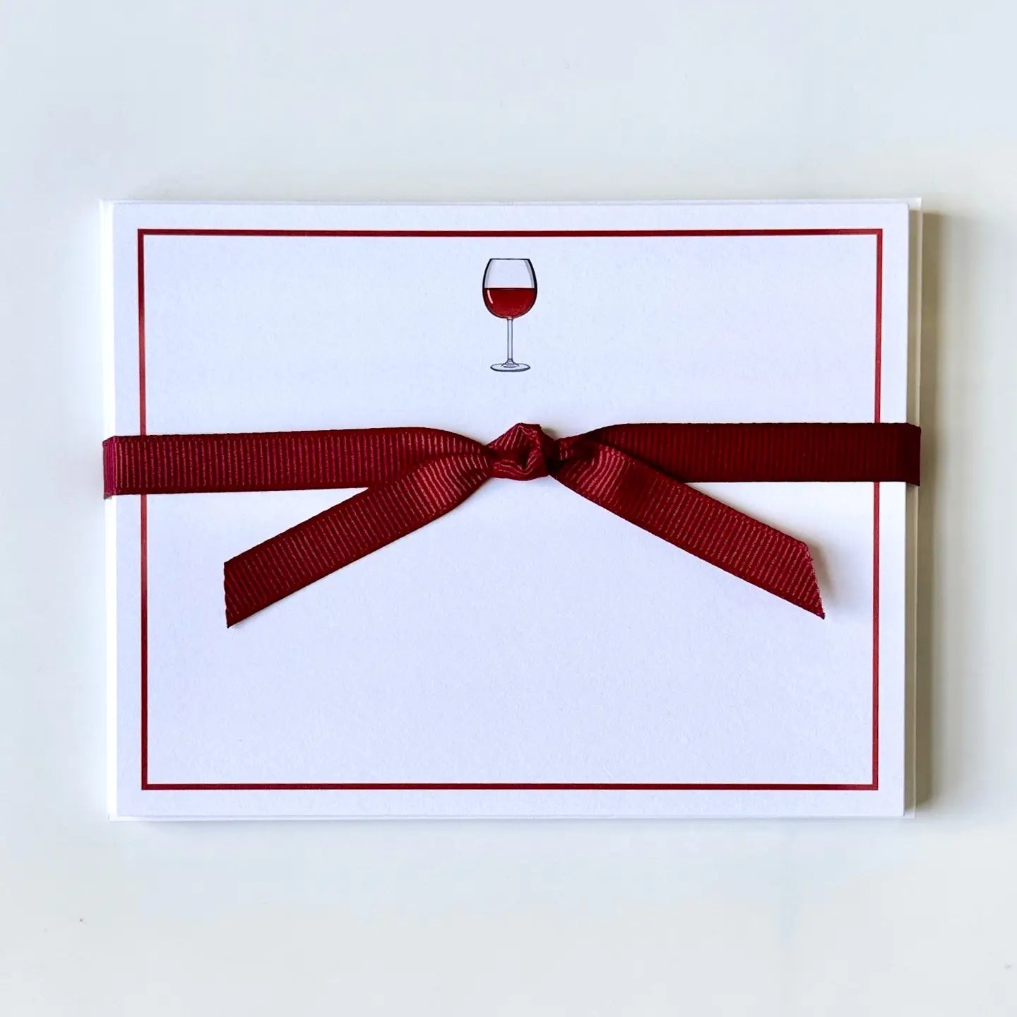 Note card with a red ribbon and a wine glass illustration on a white background