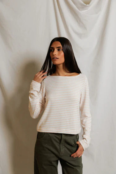 Woman wearing a white ribbed sweater and green pants against a plain background