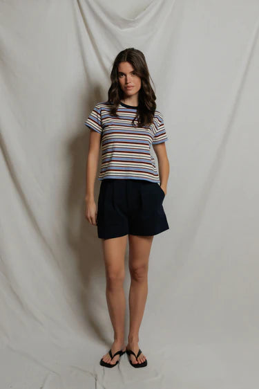 Woman wearing a striped shirt and black shorts against a plain background