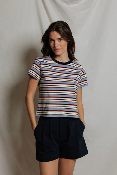 Woman wearing a striped shirt and black shorts against a plain background