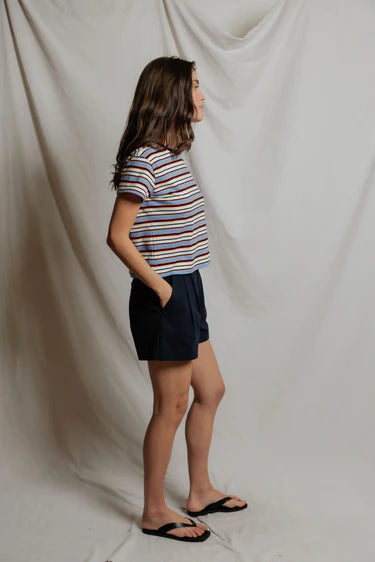Person wearing a striped shirt and dark shorts against a plain background