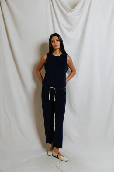 Woman wearing a navy blue outfit against a white draped curtain background