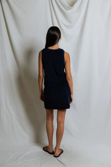 Person wearing a black sleeveless dress against a white backdrop