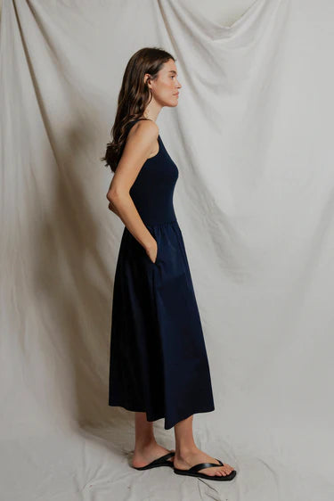 Woman wearing a navy blue dress standing against a plain white background