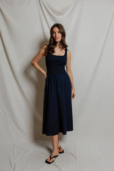 Woman wearing a navy blue dress against a plain background