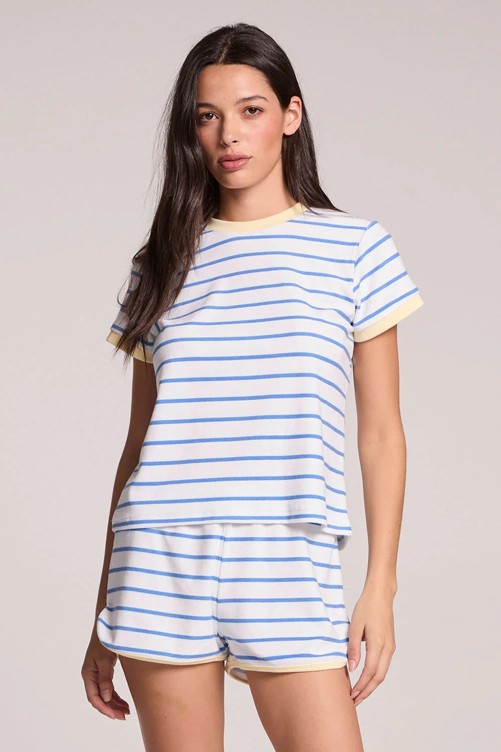 Woman wearing a blue and white striped pajama set on a plain background