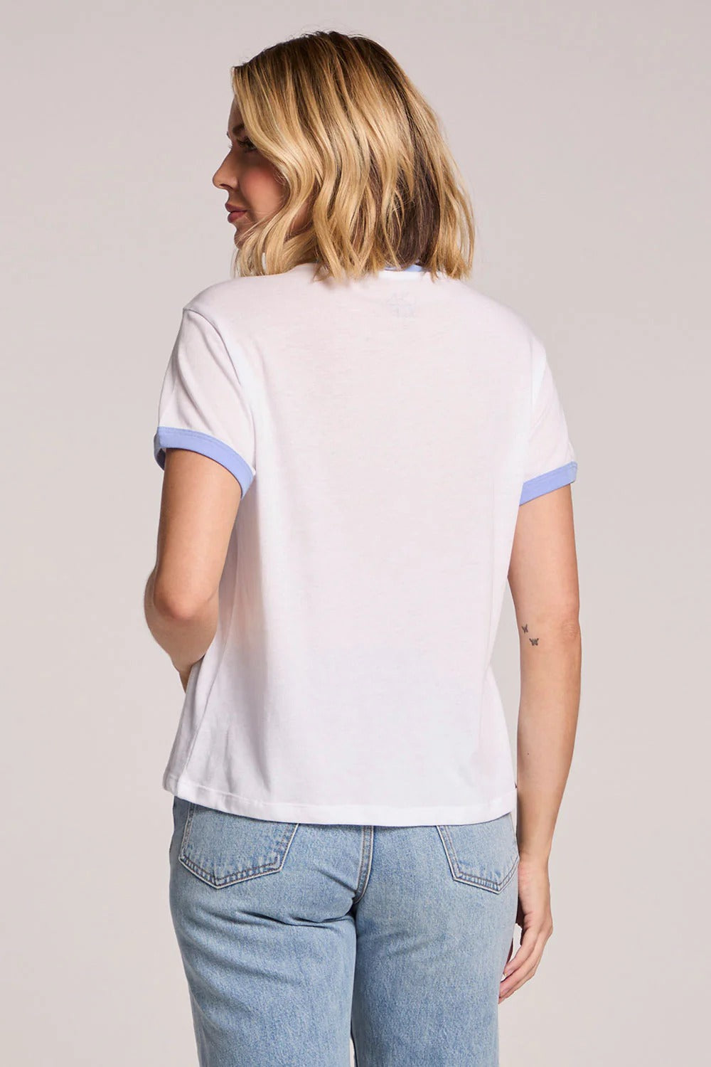 Woman wearing a white t-shirt with blue trim on a plain background