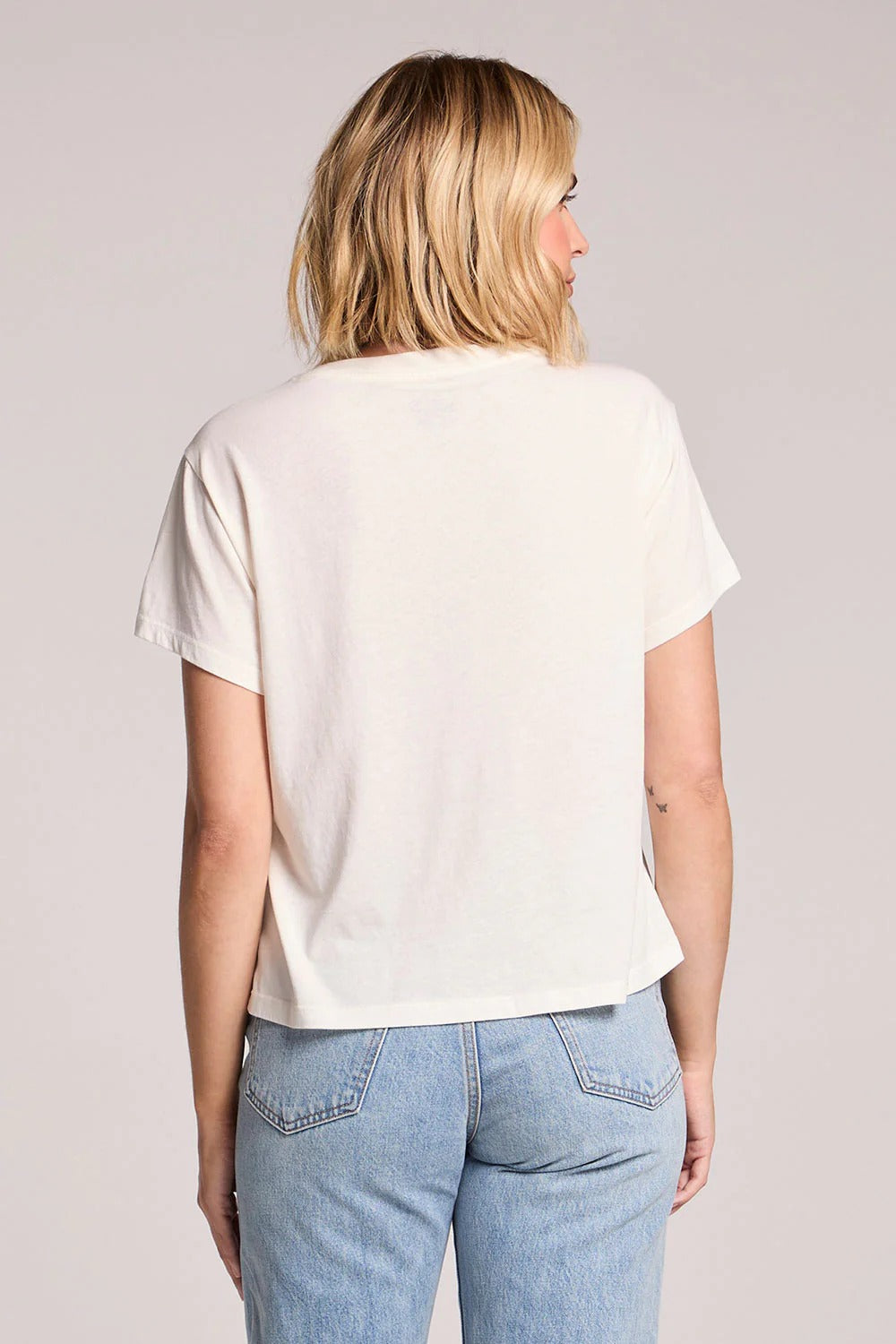 Person wearing a white t-shirt and blue jeans on a plain background