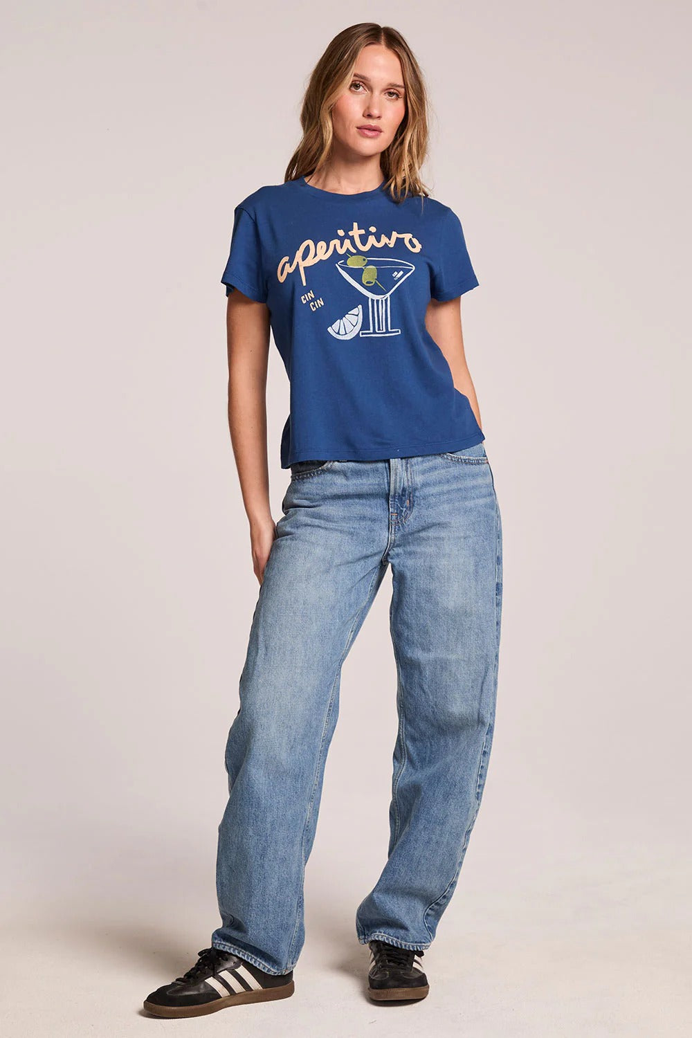 Person wearing a blue t-shirt with graphics and text, paired with light blue jeans on a plain background