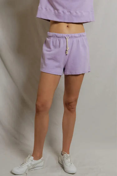 Person wearing lavender shorts and a matching top on a plain background