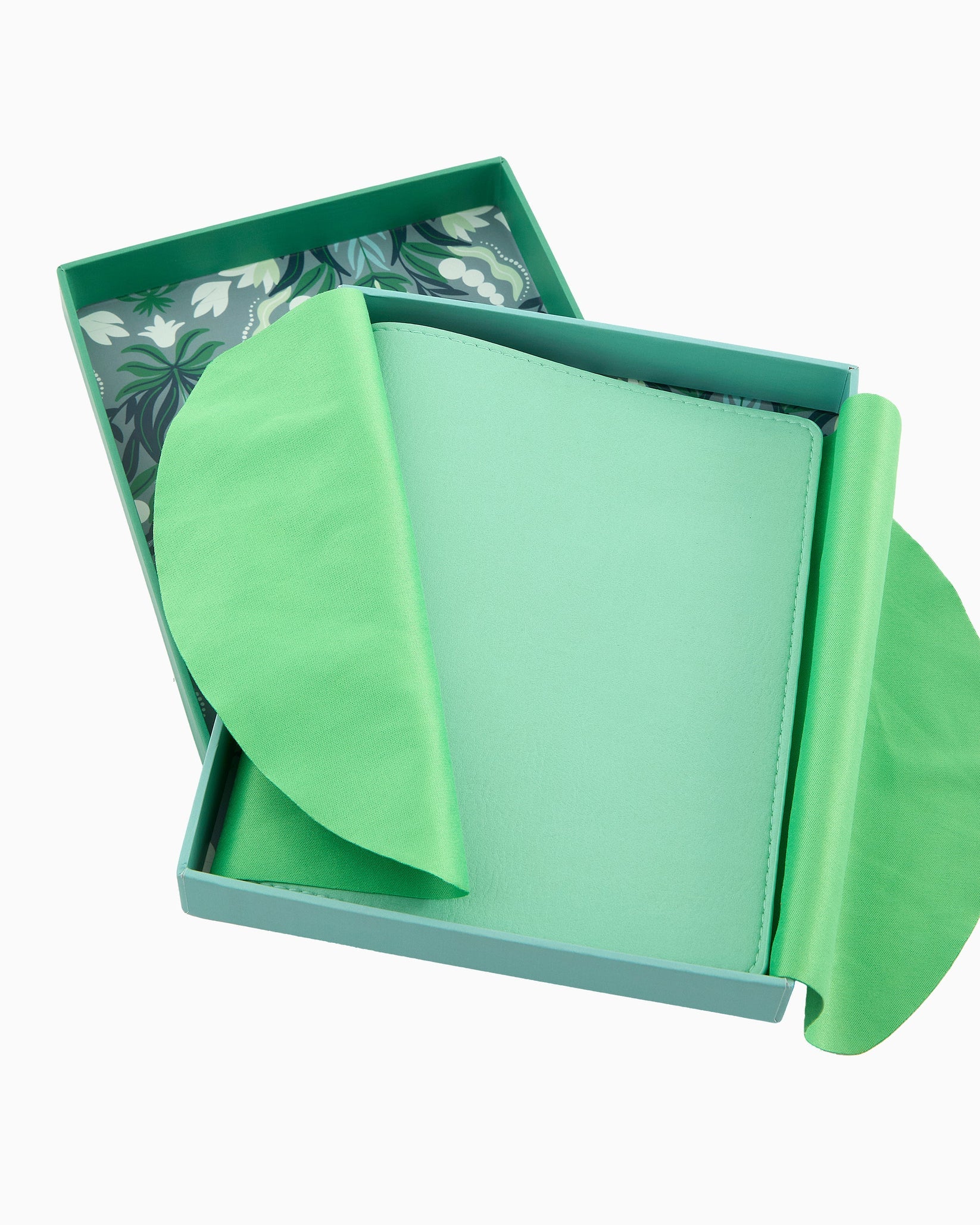 Green fabric item in a box with a floral pattern on a white background