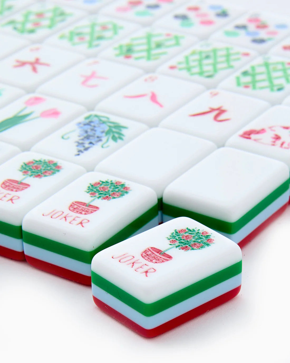 Close-up of colorful麻将 tiles with 'Joker' and floral designs on a white background